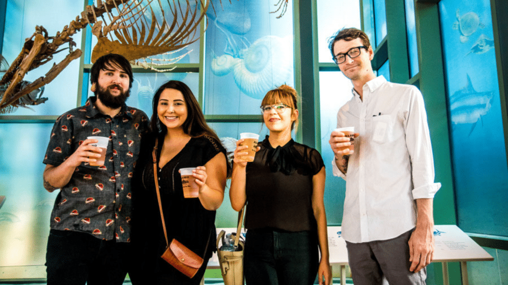 four people in casual clothing holding beers