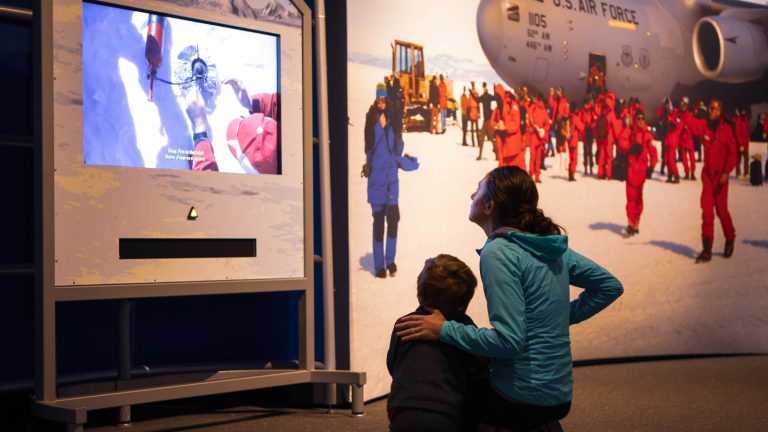 Mother and son sitting on the floor, watching a video about Antarctica.