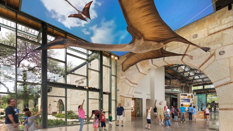 flying quetzacoatlus and museum guests pointing up.