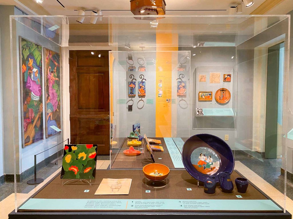 Display case inside the exhibition showing ceramic tiles, bowls and decorative serving ware.
