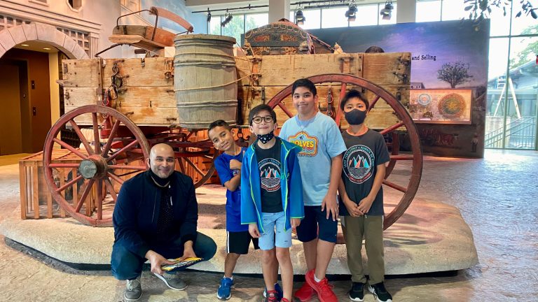 dad and four boys stand in front of wagon