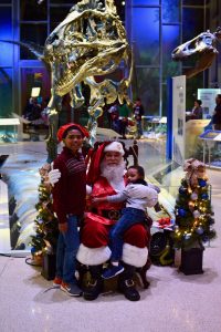 two children pose with Santa and the dinosaurs