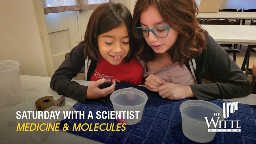 two girls peer over a science experiment.