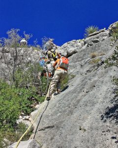 hikers repelling down side of rock.