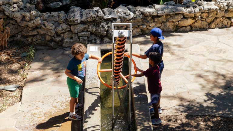 three children play with archimedes screw