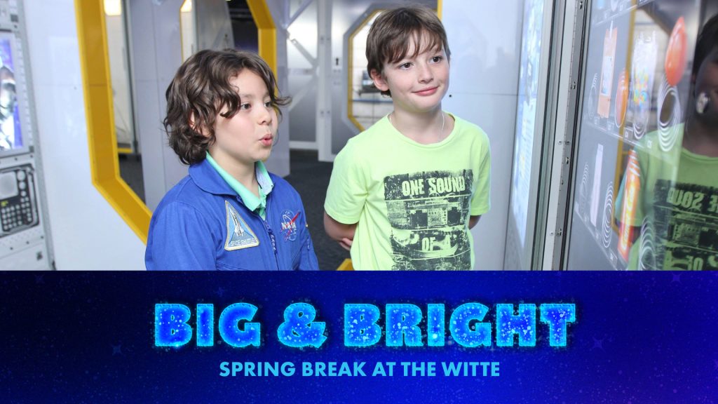 two boys smile at exhibit display.